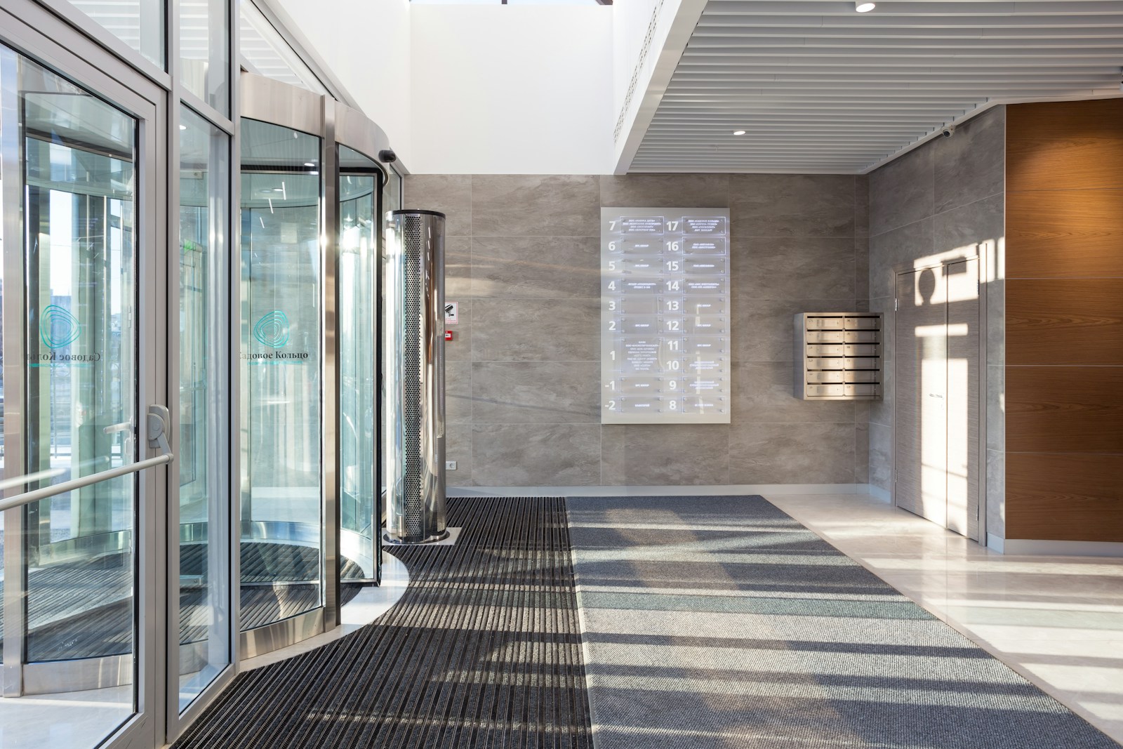 Recessed entrance matting at glass doors running into a stone-look floor with an inset border