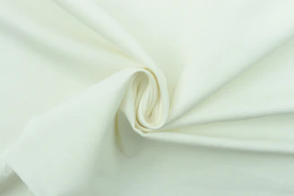 Close-up of a smooth, shimmering silk pillowcase in soft cream color.