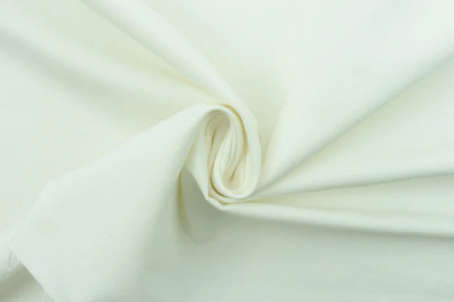 Close-up of soft organic cotton fibers arranged in a delicate spiral pattern.