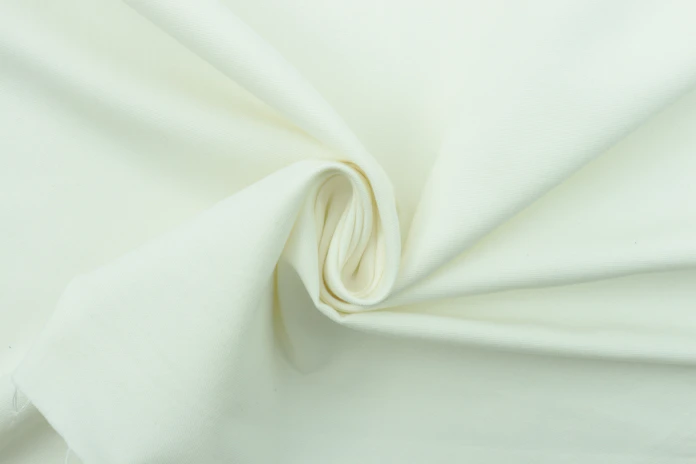 Close-up of a smooth, shimmering silk pillowcase in soft cream color.