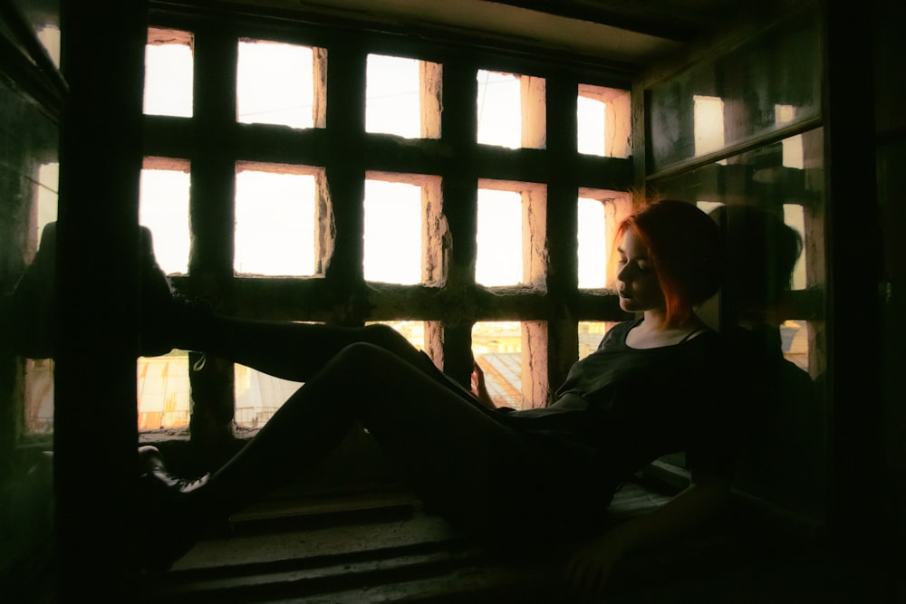 woman in black long sleeve shirt sitting on window