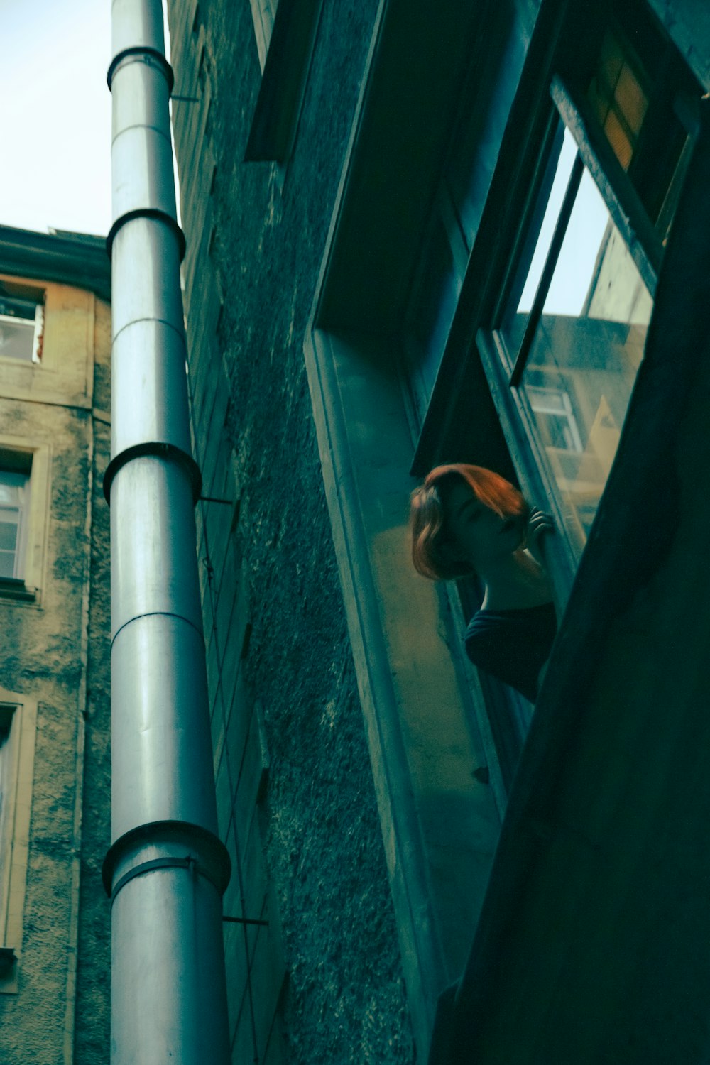 man in black jacket sitting on window during daytime