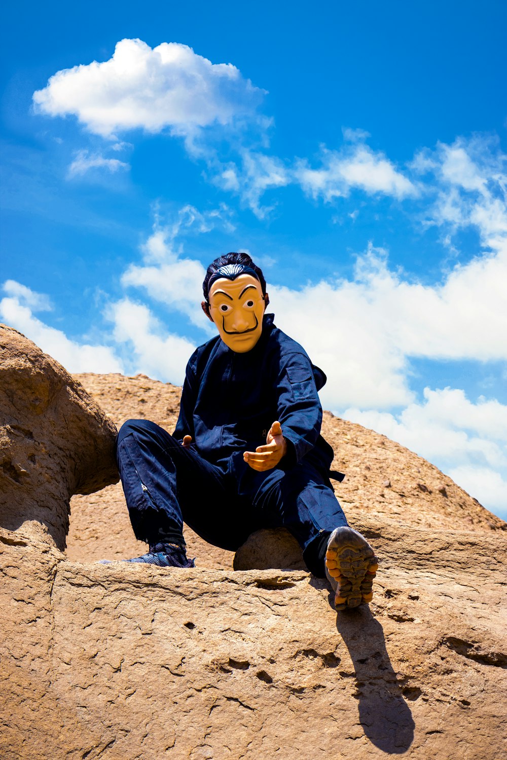 boy in black jacket sitting on brown rock during daytime