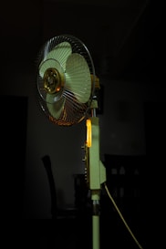 a fan sitting on top of a table next to a chair