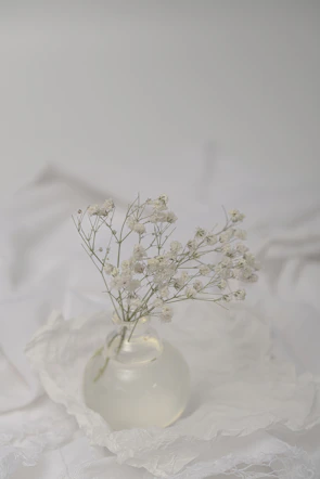 Delicate white lilies arranged with soft greenery in a clear glass vase.