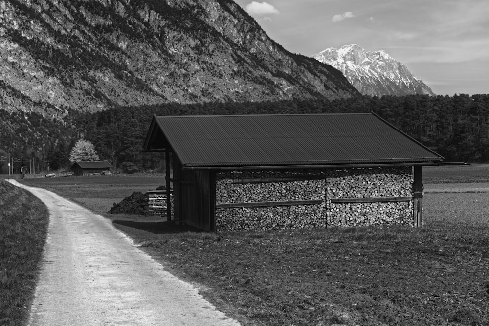 grayscale photo of wooden house near mountain