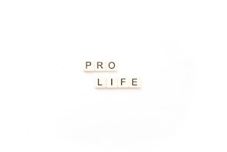 Scrabble tiles arranged to spell out the words 'PRO LIFE' on a plain white background.