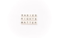 Tile letters arranged to form the words 'BABIES RIGHTS MATTER' on a white background.