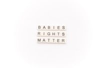 Tile letters arranged to form the words 'BABIES RIGHTS MATTER' on a white background.