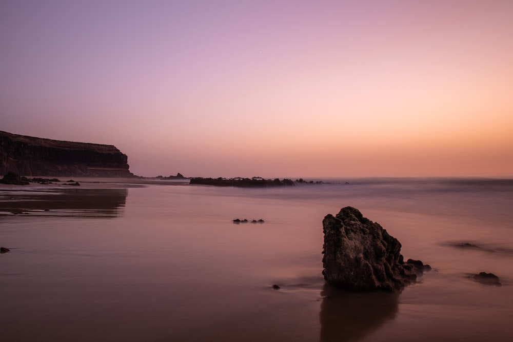 rock formation on sea during sunset