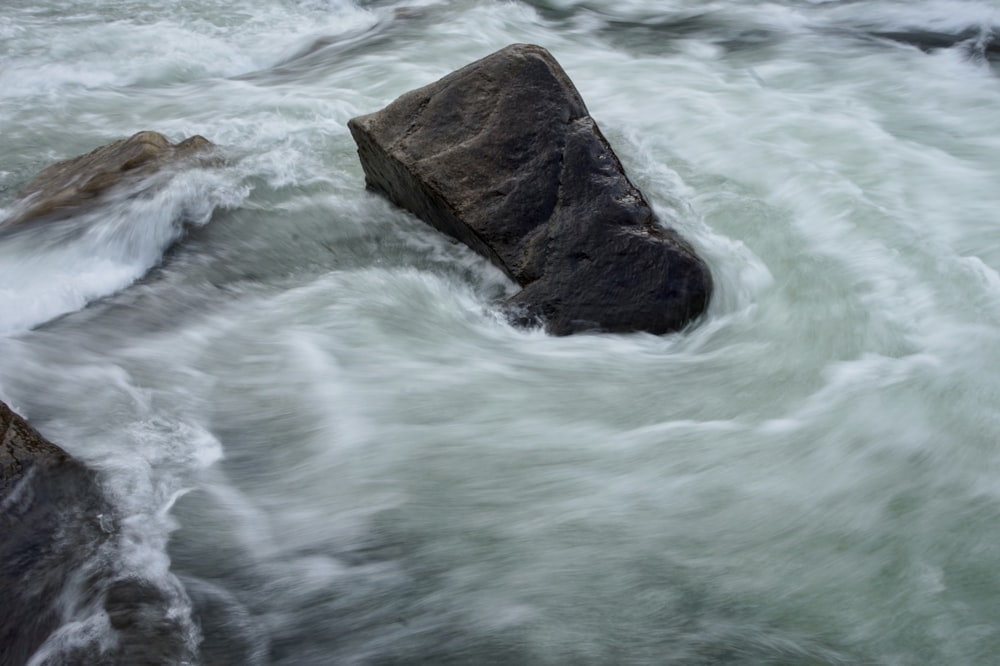 brown rock formation on body of water during daytime