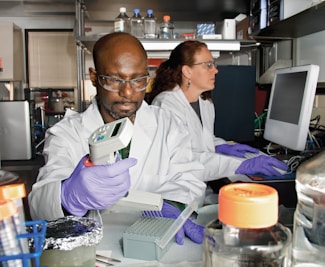 Close-up of scientists in lab coats carefully mixing chemicals in a modern pharmaceutical lab.