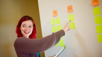 woman in gray sweater holding white and yellow sticky notes