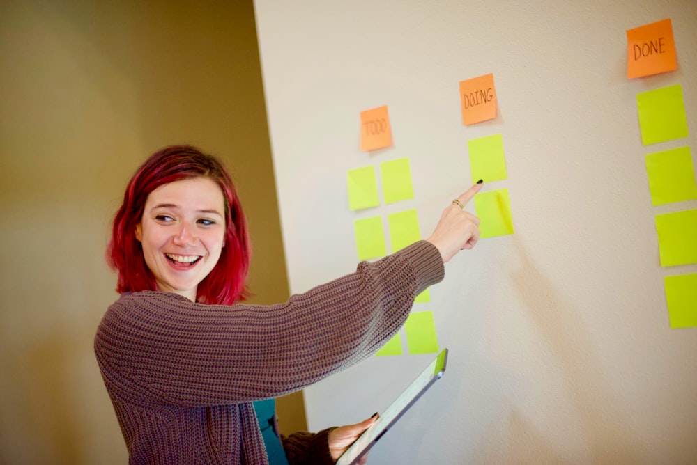 woman in gray sweater holding white and yellow sticky notes