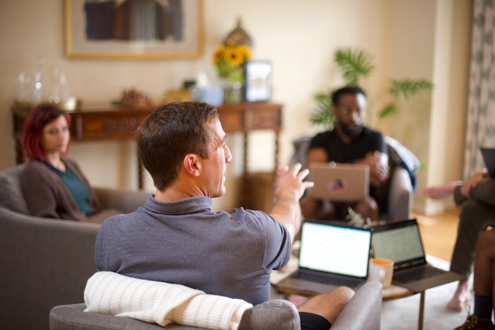 Mann im grauen Pullover sitzt auf der Couch