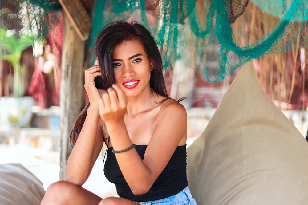 woman in black tank top and blue denim shorts sitting on white textile