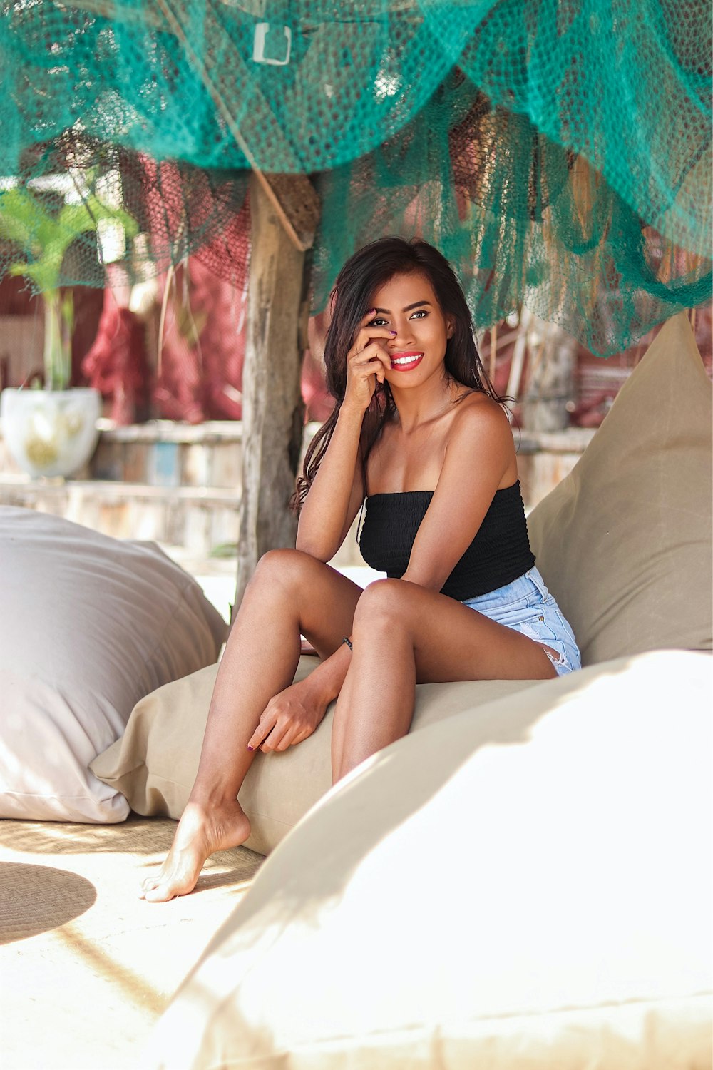 woman in black brassiere and blue shorts sitting on white bed