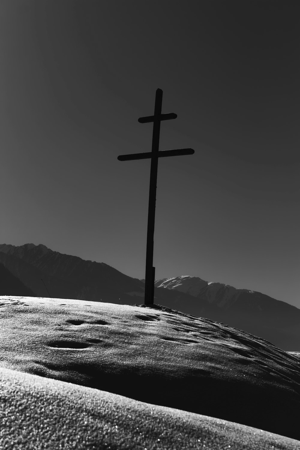 brown wooden cross on snow covered mountain during daytime