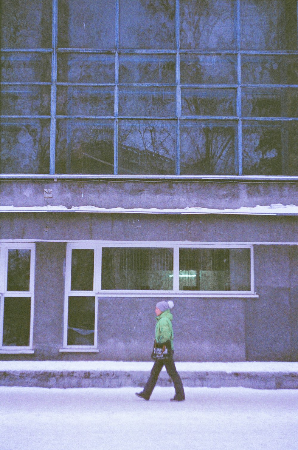 person in green jacket standing in front of window