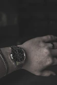 Man’s wrist adorned with a classic watch and a leather bracelet.