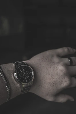 Man’s wrist adorned with a classic watch and a leather bracelet.