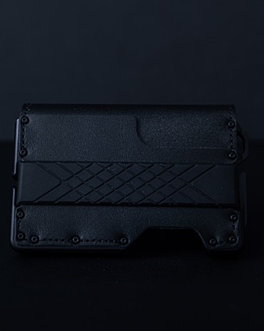 Close-up of a sleek black wallet engraved with an intricate geometric pattern glowing softly under moody lighting.