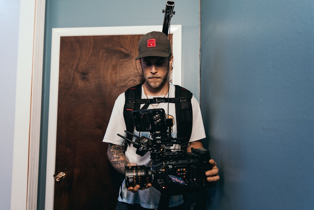 man in black and white crew neck t-shirt holding black dslr camera