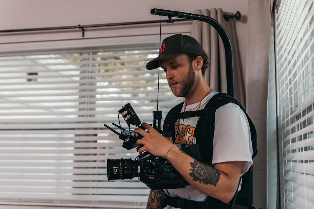 man in white and black crew neck t-shirt holding black dslr camera