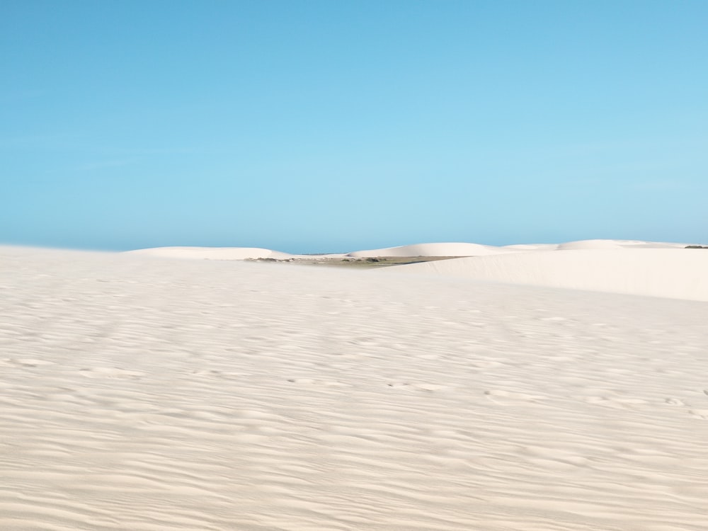 sable blanc sous le ciel bleu pendant la journée