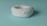A soft, cushion-like object with a rounded, pillow-like shape is placed on a smooth, teal-colored surface. The object appears plush and somewhat irregular in form, suggesting a comfortable, inviting texture.
