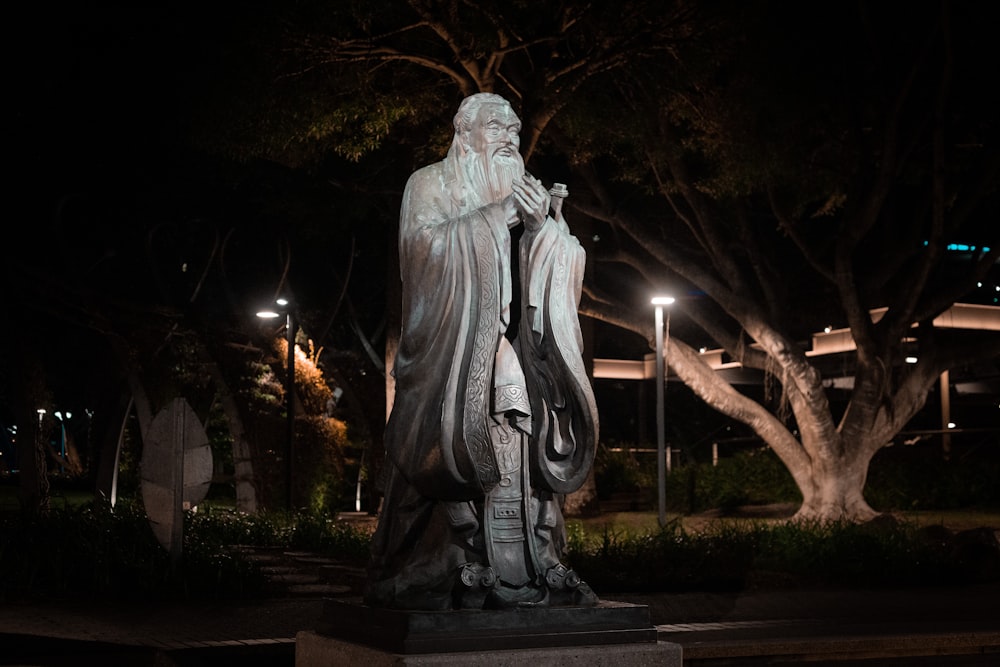 angel statue near green trees during night time