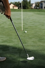 person holding golf club and golf ball