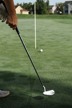 person holding golf club and golf ball