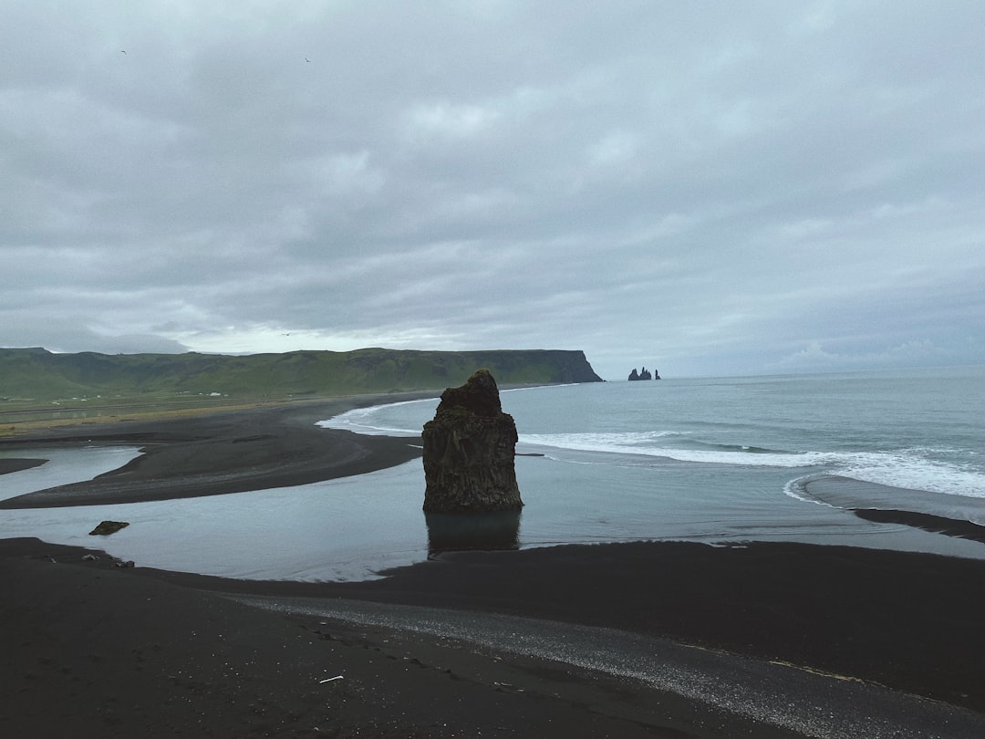 brown rock formation on sea shore under white clouds during daytime