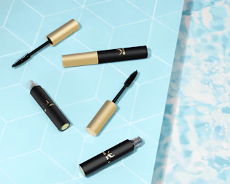 Elegant mascaras and eyeliners displayed with delicate floral accents