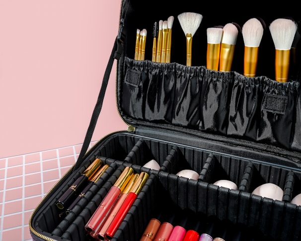 Stylish makeup brushes and vibrant lipsticks displayed on a clean white background with gold highlights.
