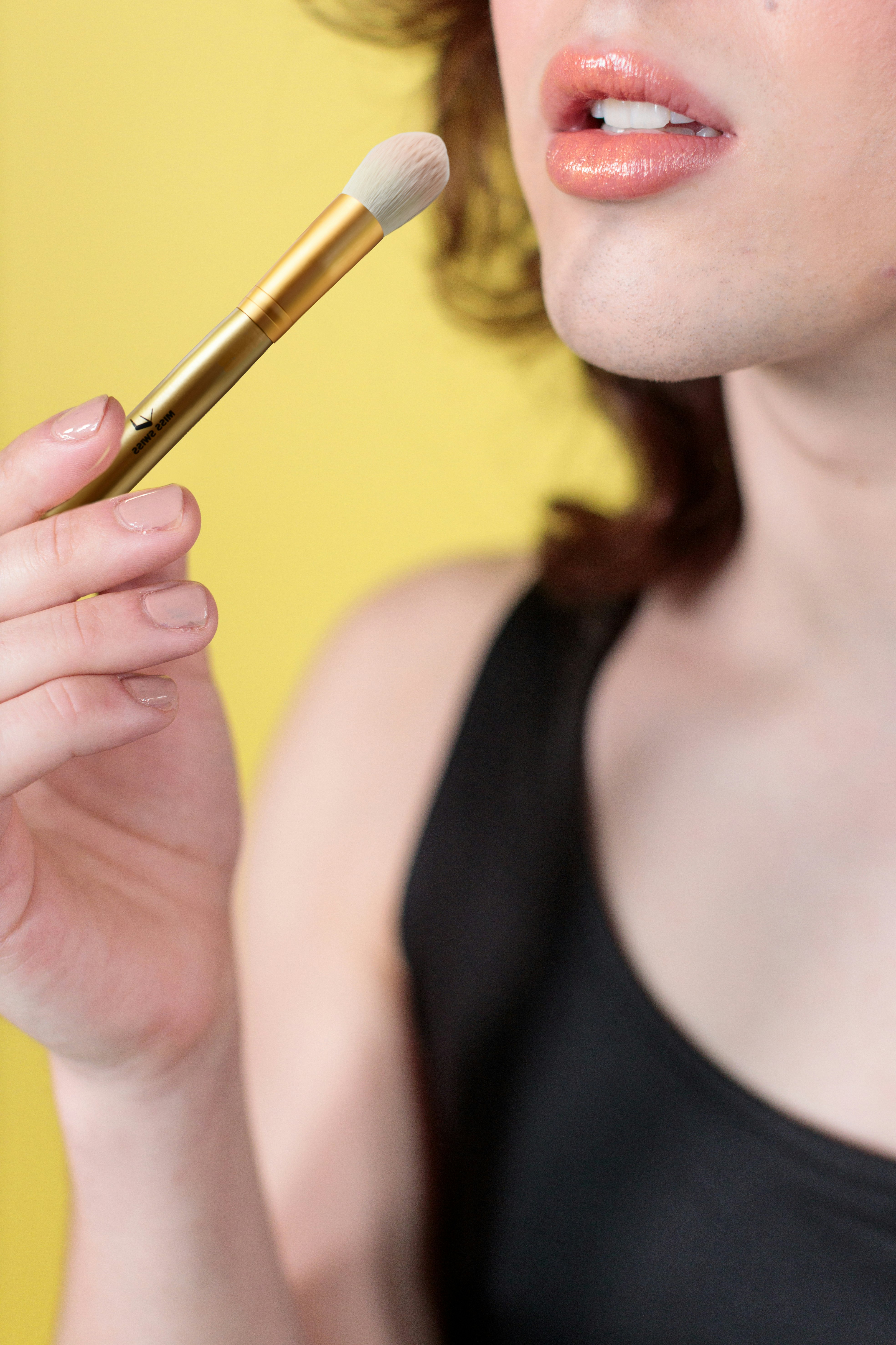 woman in black tank top holding gold pen