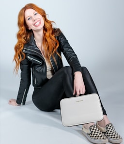 woman in black leather jacket and black pants sitting on white table