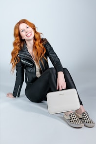 woman in black leather jacket and black pants sitting on white table