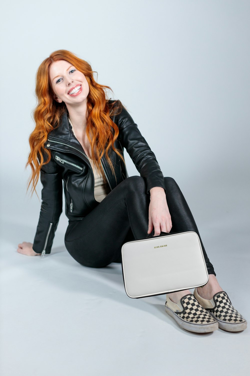 woman in black leather jacket and black pants sitting on white table