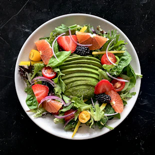 a white plate topped with a salad covered in fruit