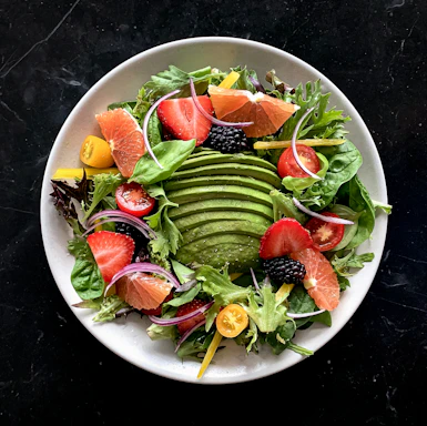 a white plate topped with a salad covered in fruit