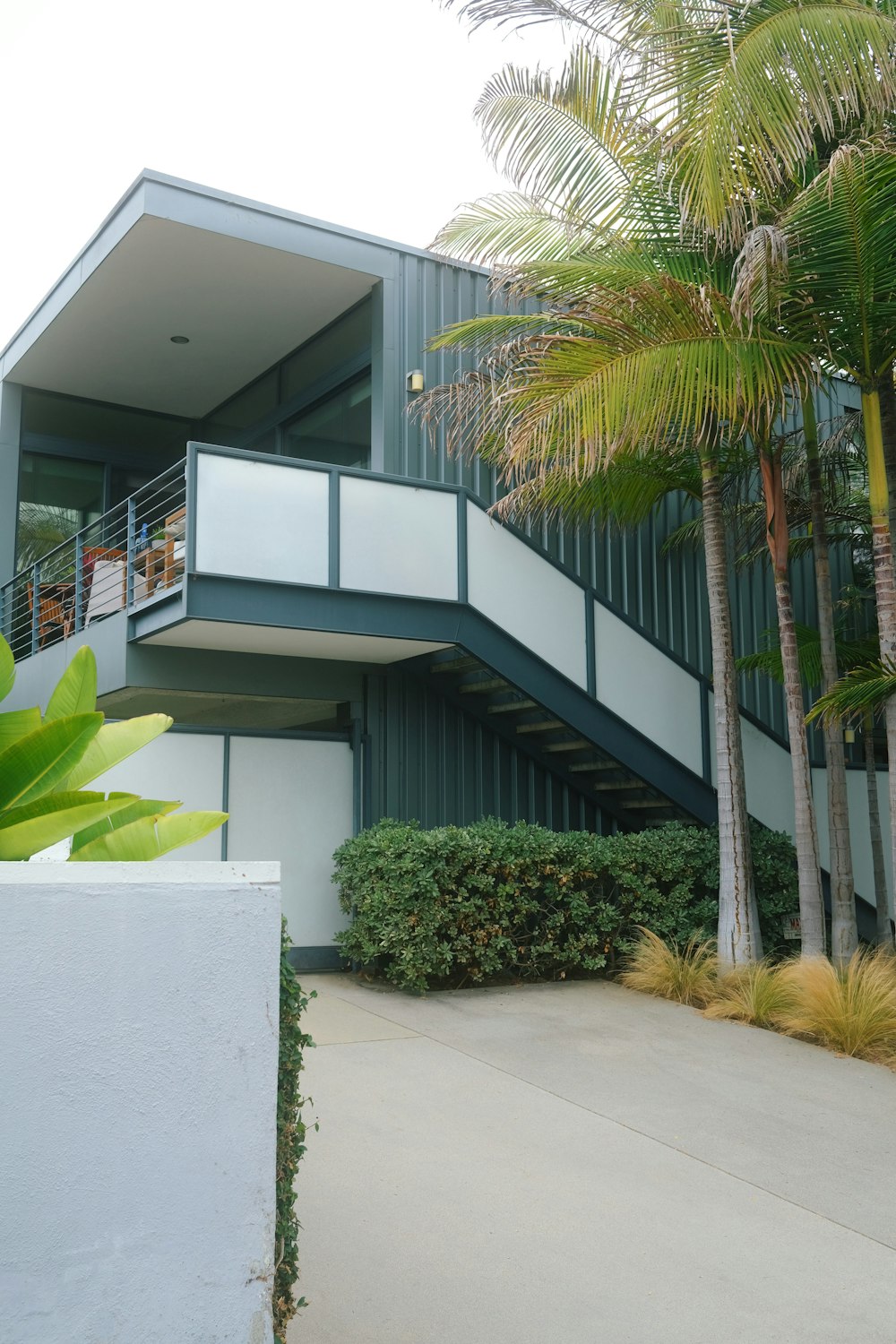 a building with a balcony and palm trees in front of it