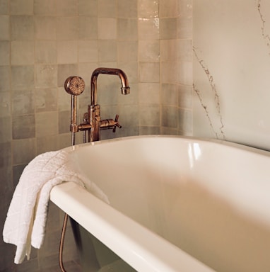 white ceramic bathtub with stainless steel shower head