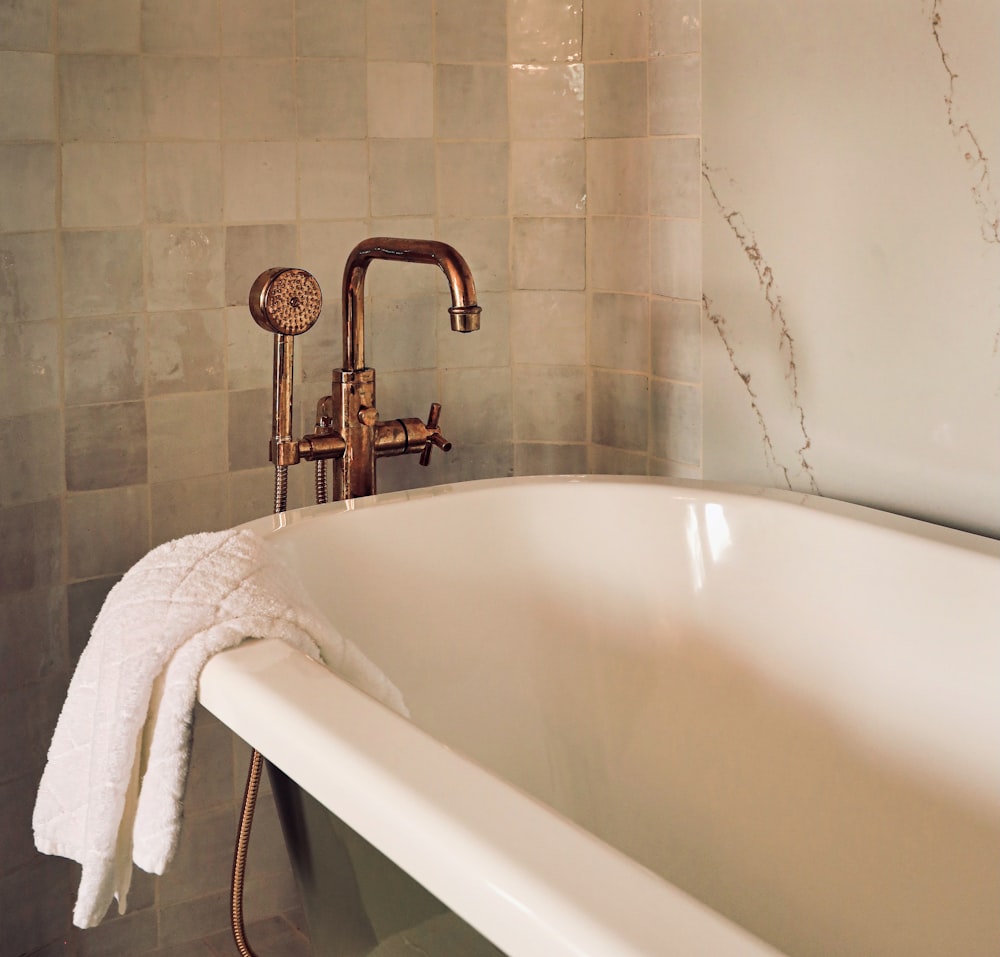 white ceramic bathtub with stainless steel shower head