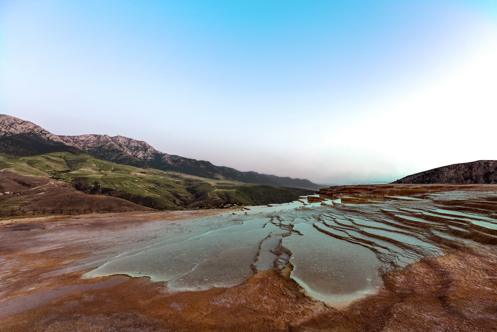 Montañas marrones y verdes junto al cuerpo de agua durante el día