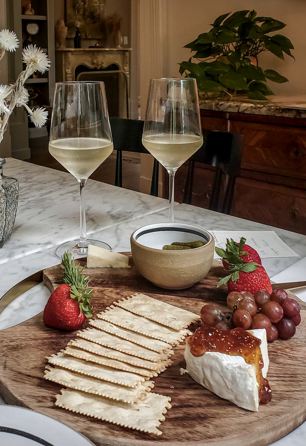 a plate of cheese, crackers, strawberries, and a glass of wine