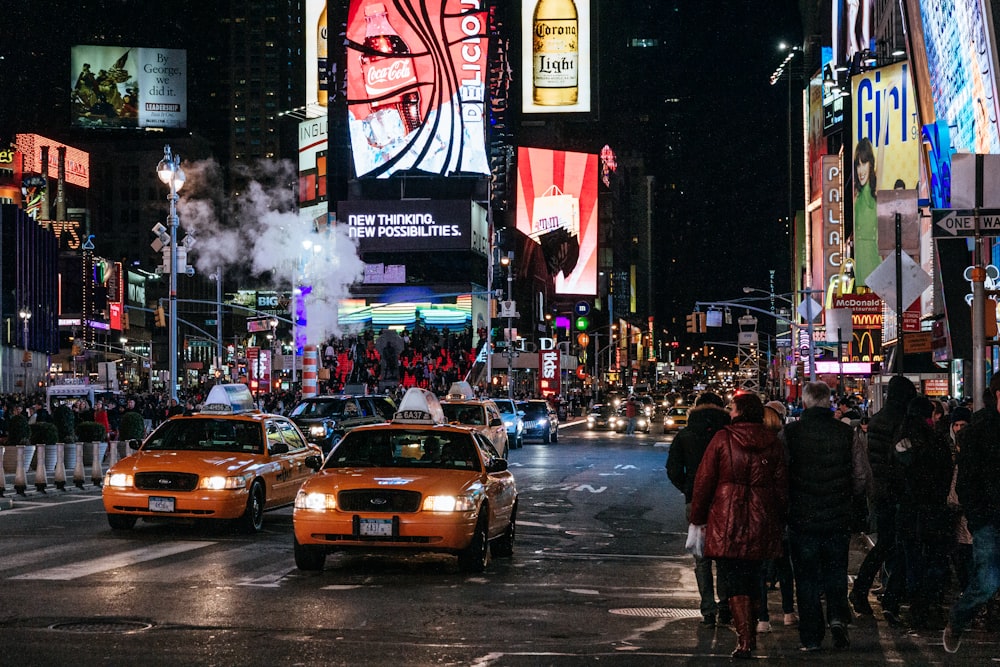 people walking on street with cars on road during nighttime