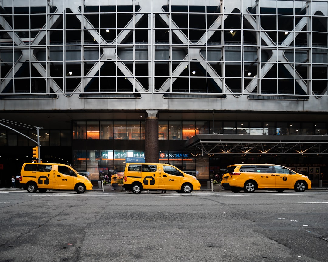 yellow taxi cab on road near white building