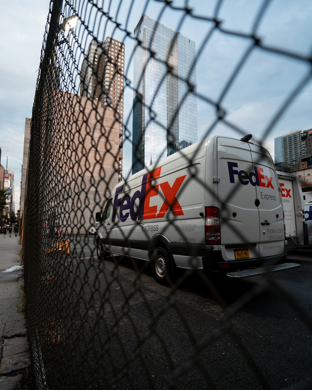 white and red van parked beside gray metal fence during daytime